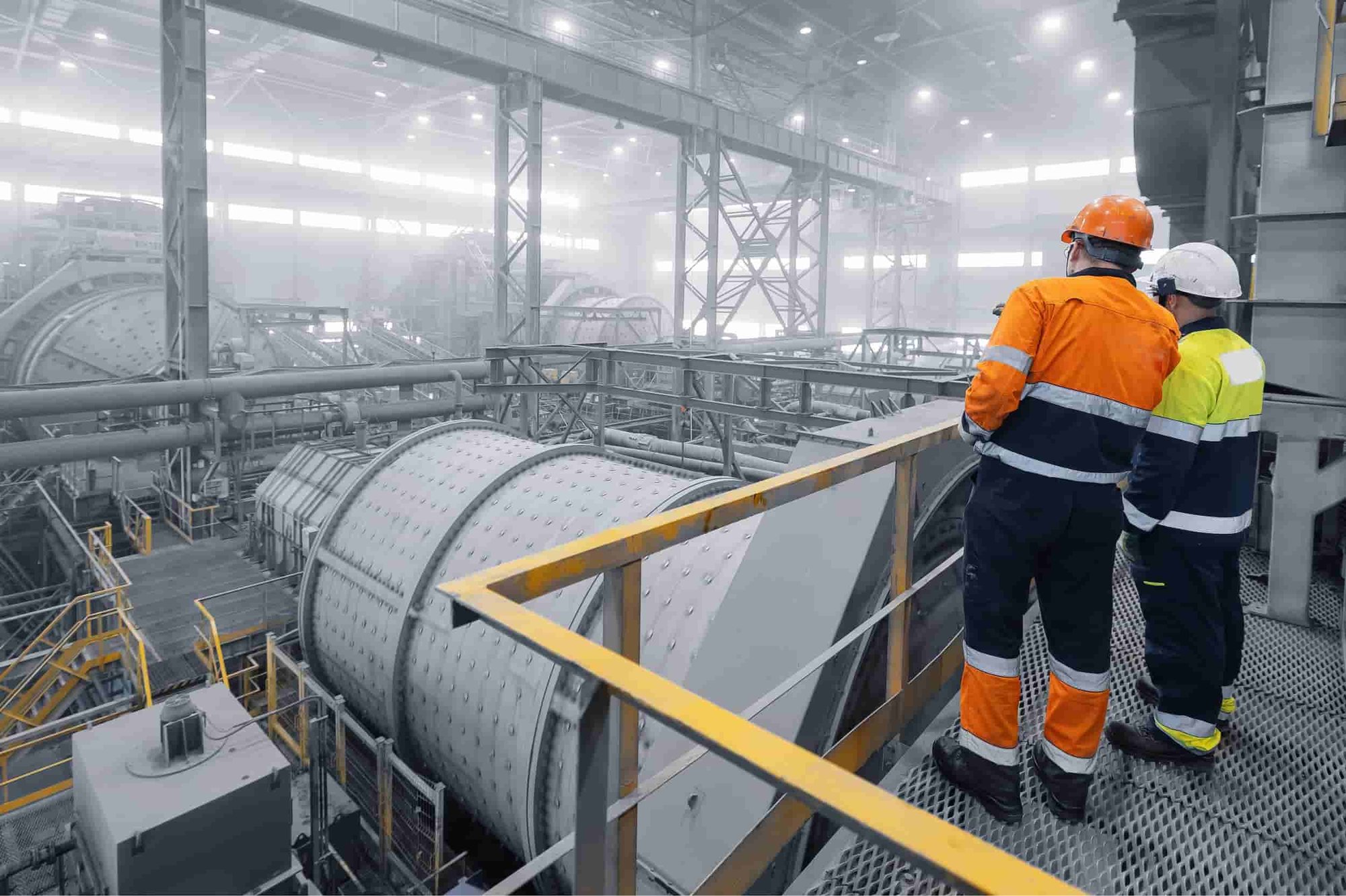 Industrial manufacturing recruiters: two professionals overlooking heavy processing equipment in a manufacturing plant