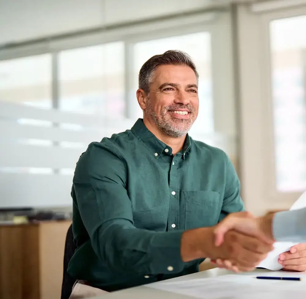 man at desk shaking hands