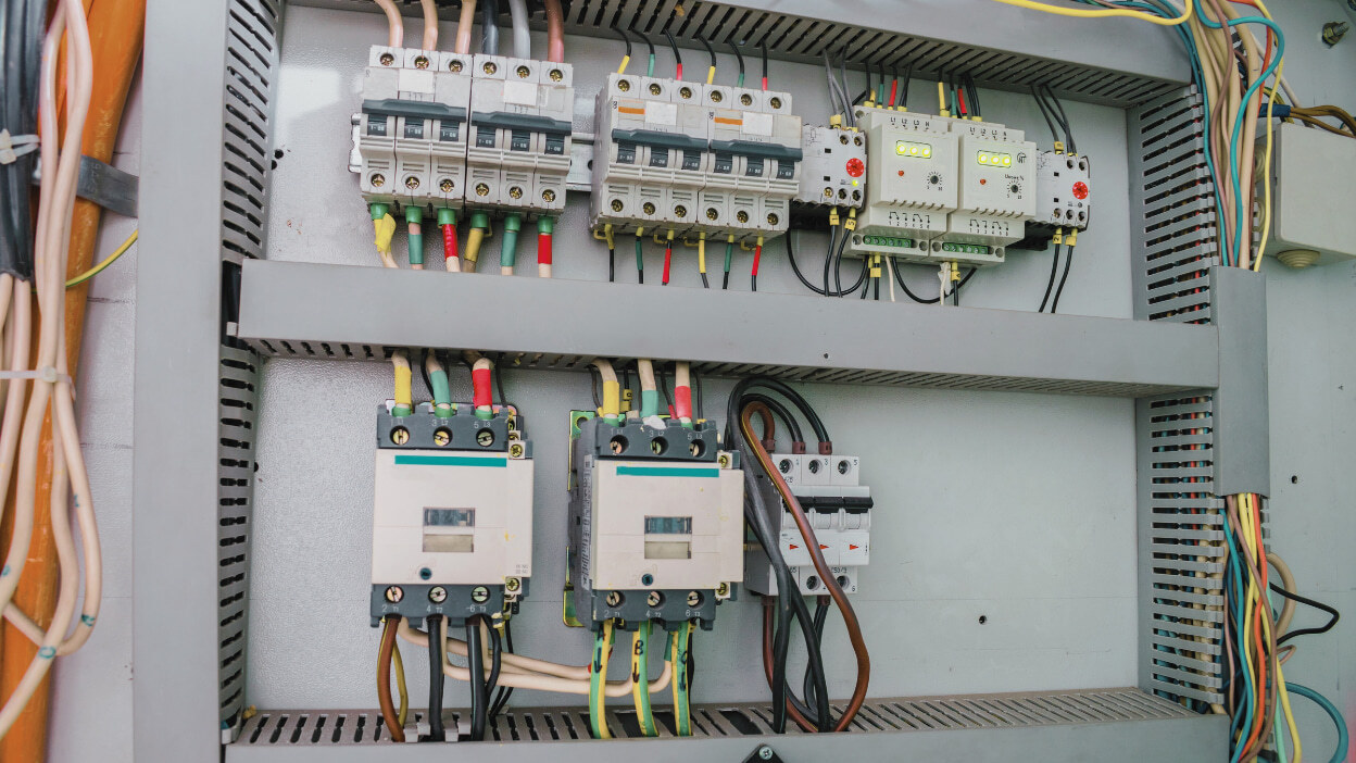 Electrical control panel with circuit breakers and contactors in a manufacturing facility.