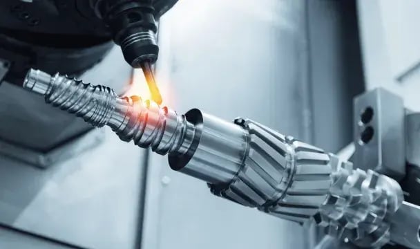 CNC machine cutting a precision metal gear shaft at an industrial machinery manufacturer