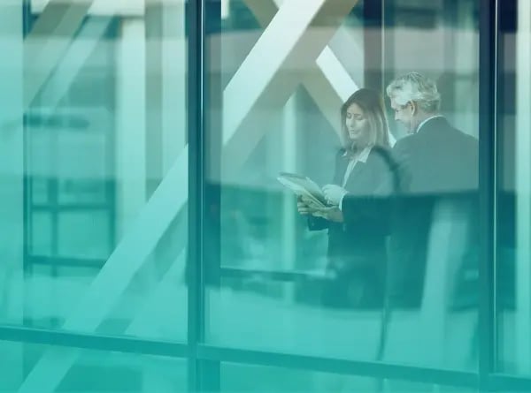 Two executives reviewing a document together behind a glass office wall