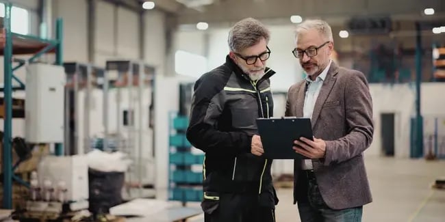 Plant supervisor and manager reviewing a clipboard together on the production floor