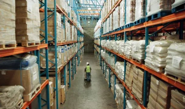 Worker moving inventory through the aisle of a wholesale distribution warehouse