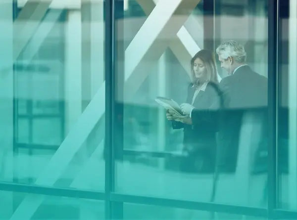 Two executives reviewing a document together behind a glass office wall