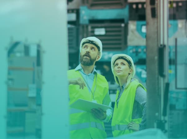 Plant engineering manager and colleague reviewing production equipment on a manufacturing floor
